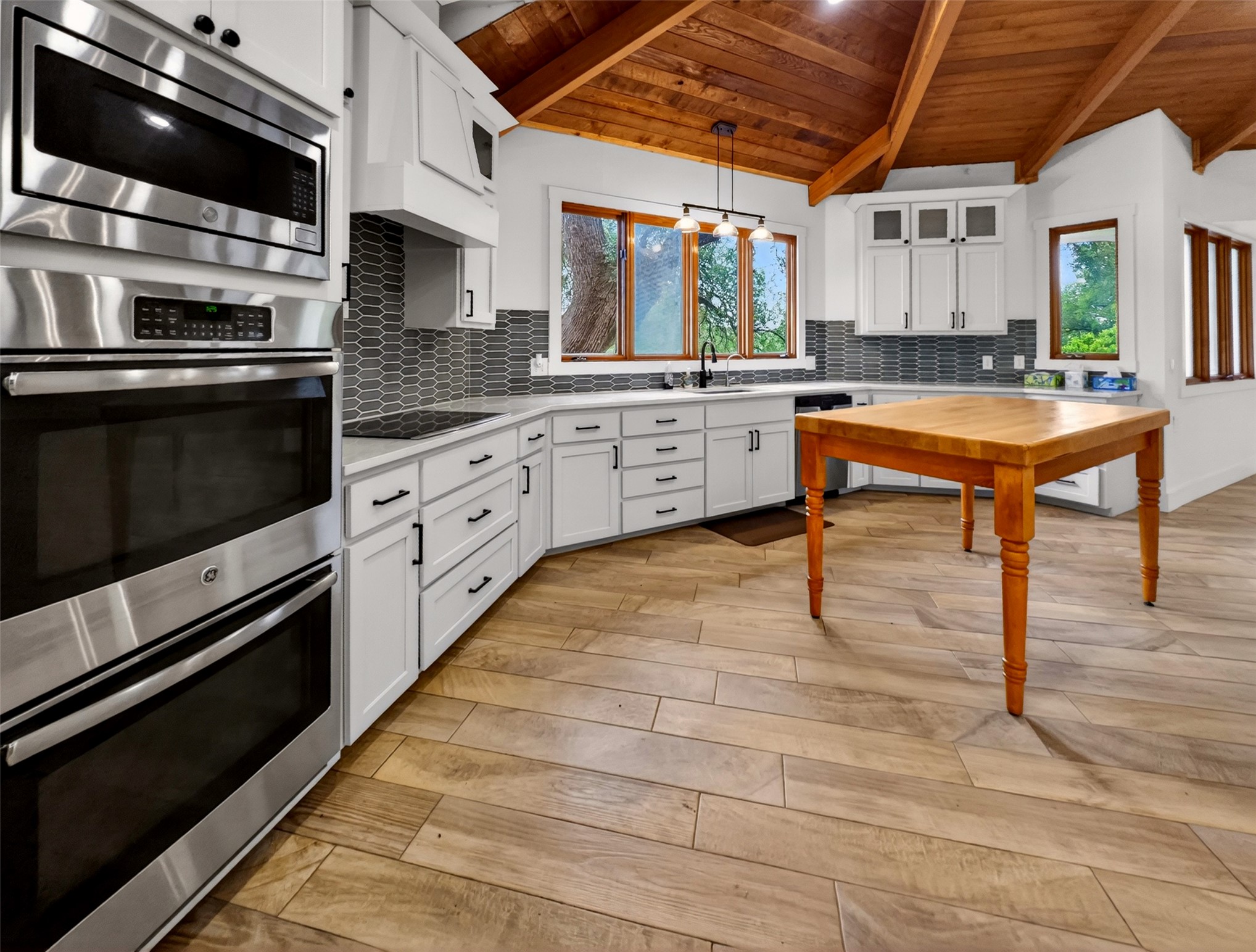 6106 Southeast Fm Ranch Buckholts, TX 76518 - Photo 7 of 38 Well-appointed kitchen featuring a vaulted wood-paneled ceiling, white cabinetry with black hardware, stainless steel appliances including a double oven and microwave, and wood-look tile flooring