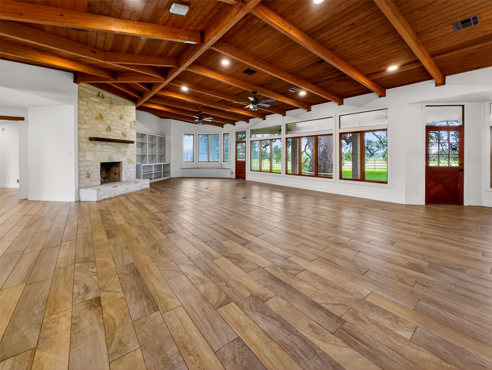 6106 Southeast Fm Ranch Buckholts, TX 76518 - Photo 10 of 38 Expansive living area featuring a vaulted wood-beamed ceiling, a stone fireplace, built-in shelving, wood-look flooring, and a wall of windows offering views of the outdoors