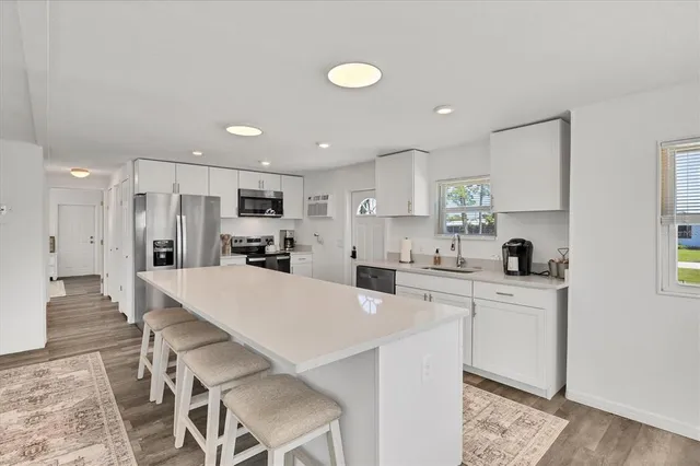 a kitchen with a refrigerator a stove a sink a dining table and chairs