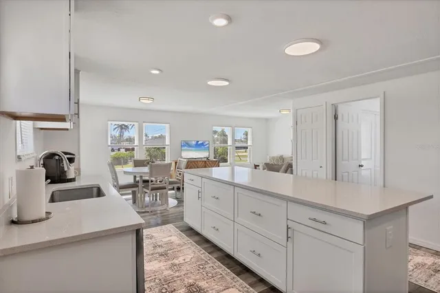 a large white kitchen with sink and cabinets