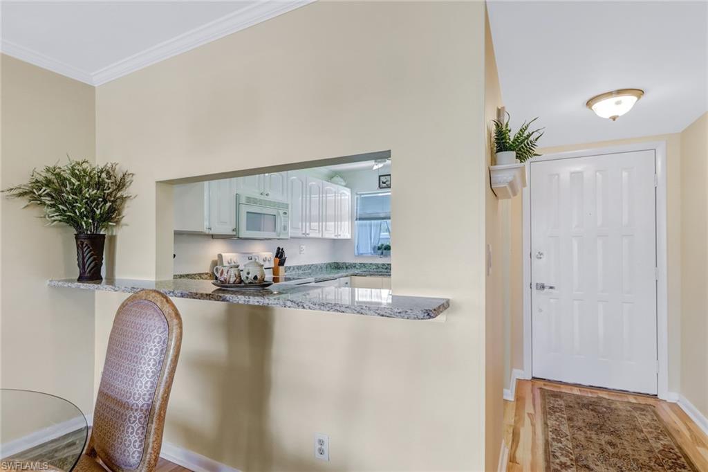 49 High Point Circle South, Unit 104 Naples, FL 34103 - Photo 11 of 30 a kitchen with kitchen island a dining table chairs cabinets and stainless steel appliances