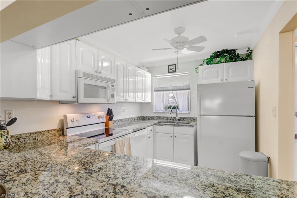 49 High Point Circle South, Unit 104 Naples, FL 34103 - Photo 12 of 30 a kitchen with stainless steel appliances granite countertop a refrigerator sink and cabinets