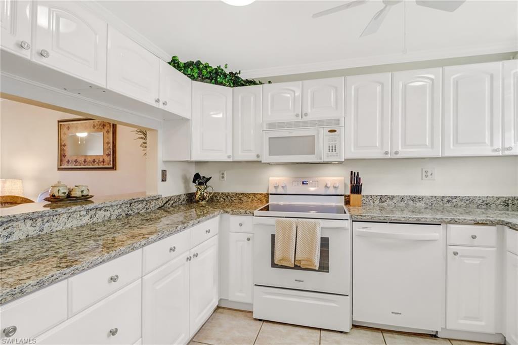49 High Point Circle South, Unit 104 Naples, FL 34103 - Photo 13 of 30 a kitchen with granite countertop white cabinets and white appliances