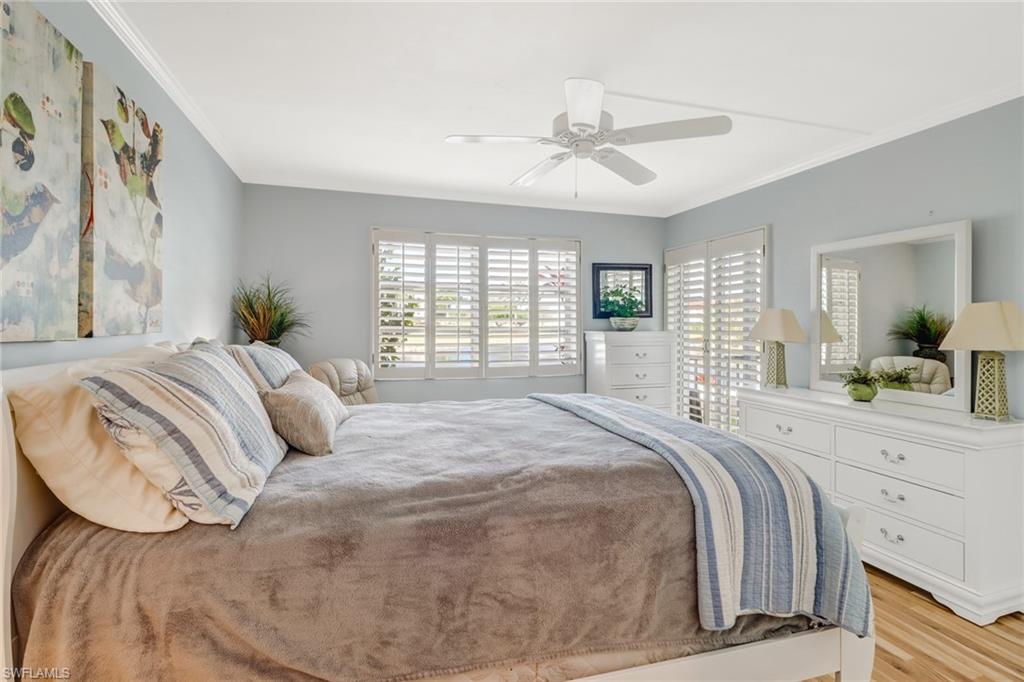 49 High Point Circle South, Unit 104 Naples, FL 34103 - Photo 17 of 30 a bedroom with a large bed and a chandelier