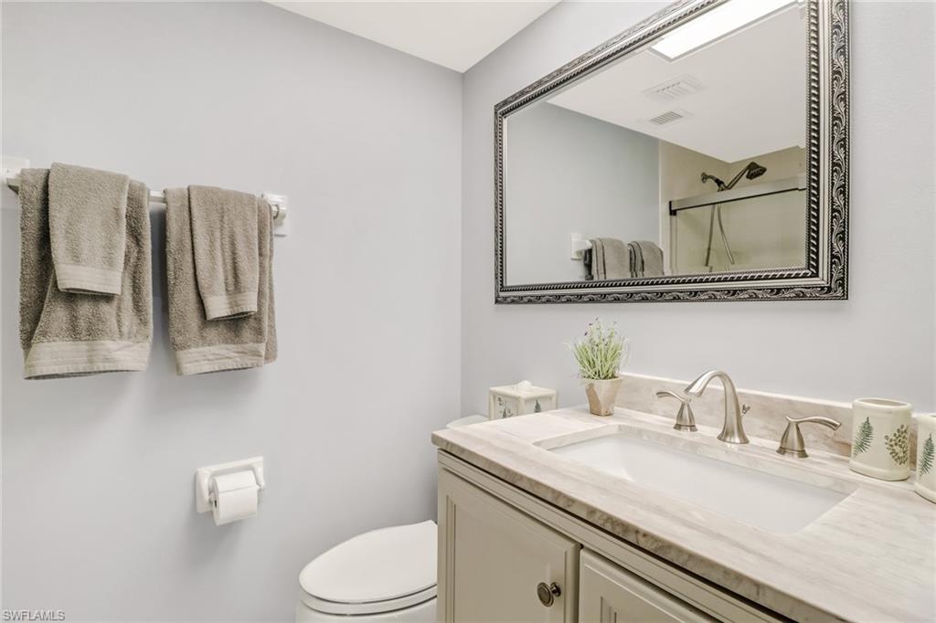 49 High Point Circle South, Unit 104 Naples, FL 34103 - Photo 18 of 30 a bathroom with a granite countertop sink a toilet and a mirror