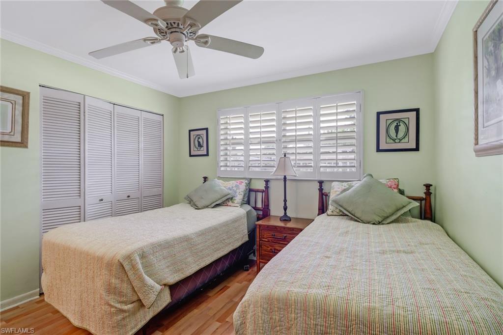 49 High Point Circle South, Unit 104 Naples, FL 34103 - Photo 20 of 30 a bedroom with two beds and a chandelier