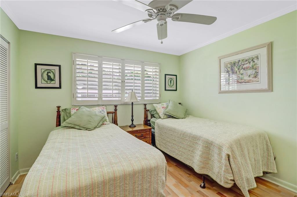 49 High Point Circle South, Unit 104 Naples, FL 34103 - Photo 21 of 30 a bedroom with a bed and a chandelier