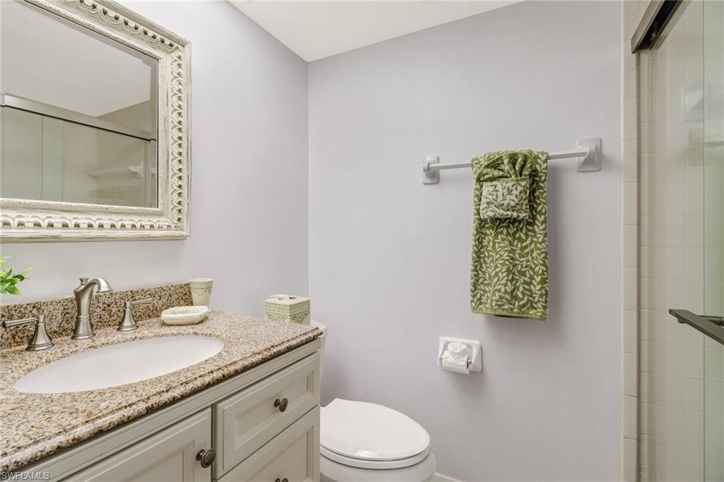 49 High Point Circle South, Unit 104 Naples, FL 34103 - Photo 22 of 30 a bathroom with a granite countertop sink a toilet and shower