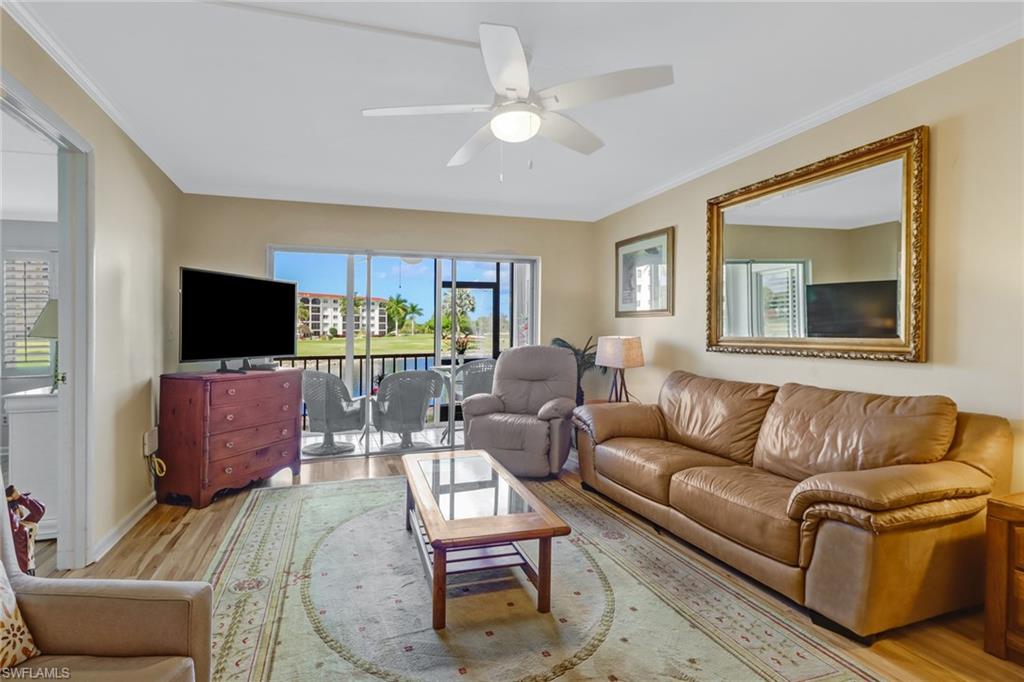 49 High Point Circle South, Unit 104 Naples, FL 34103 - Photo 5 of 30 a living room with furniture a flat screen tv and a large window