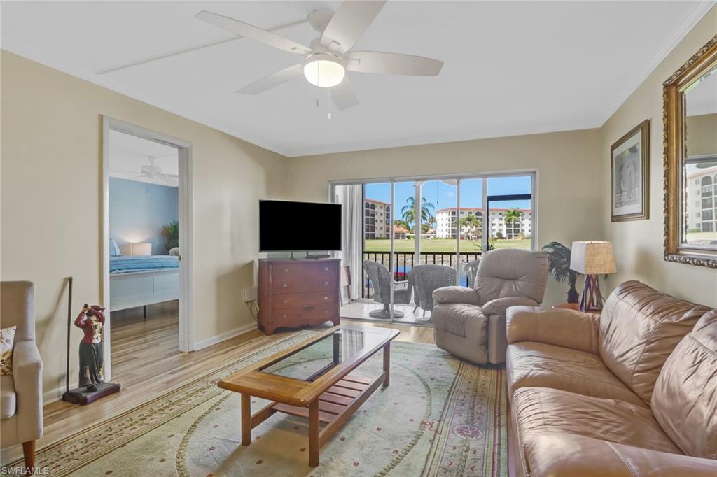 49 High Point Circle South, Unit 104 Naples, FL 34103 - Photo 6 of 30 a living room with furniture a flat screen tv and a large window