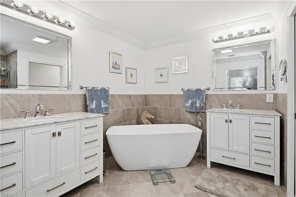 a spacious bathroom with a double vanity sink mirror and bathtub