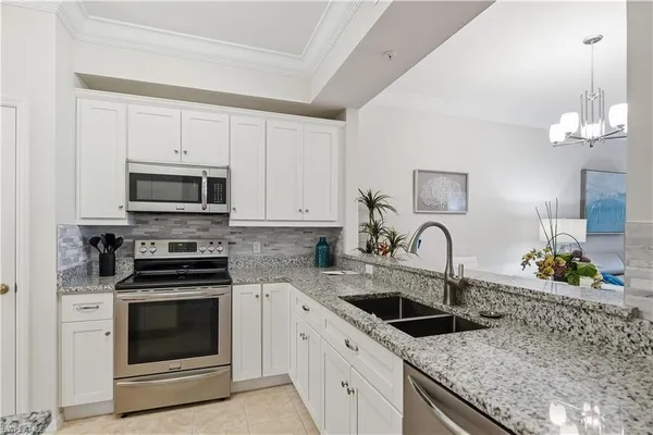 a kitchen with granite countertop a sink stove and microwave
