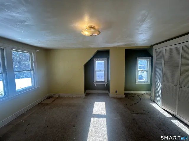 a view of an empty room with a fireplace and windows