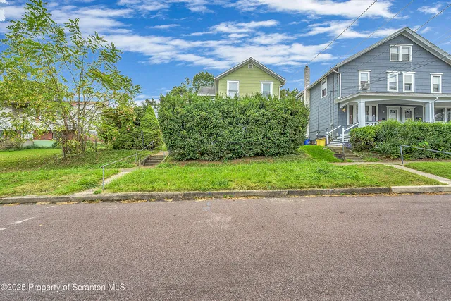 a view of a house with a yard and large trees