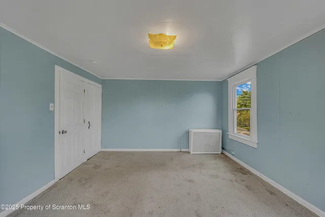 a view of an empty room with window and stairs