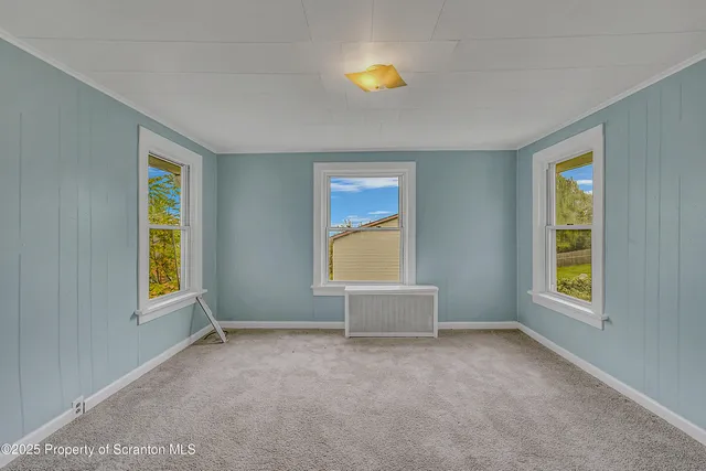 a view of an empty room with a window and a kitchen