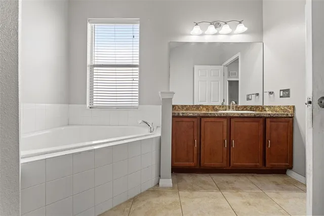 a bathroom with a tub a sink and mirror