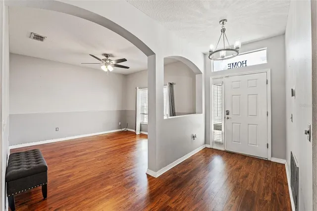 a view of empty room with wooden floor and ceiling fan