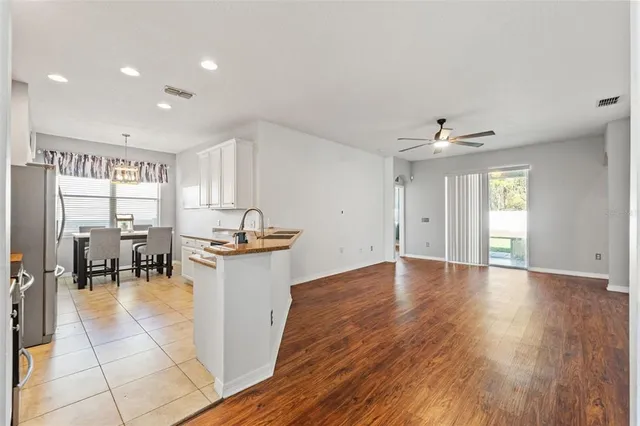 a view of a kitchen with kitchen island stainless steel appliances a dining table chairs and sink