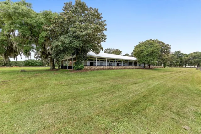 a view of a house with a big yard and large trees