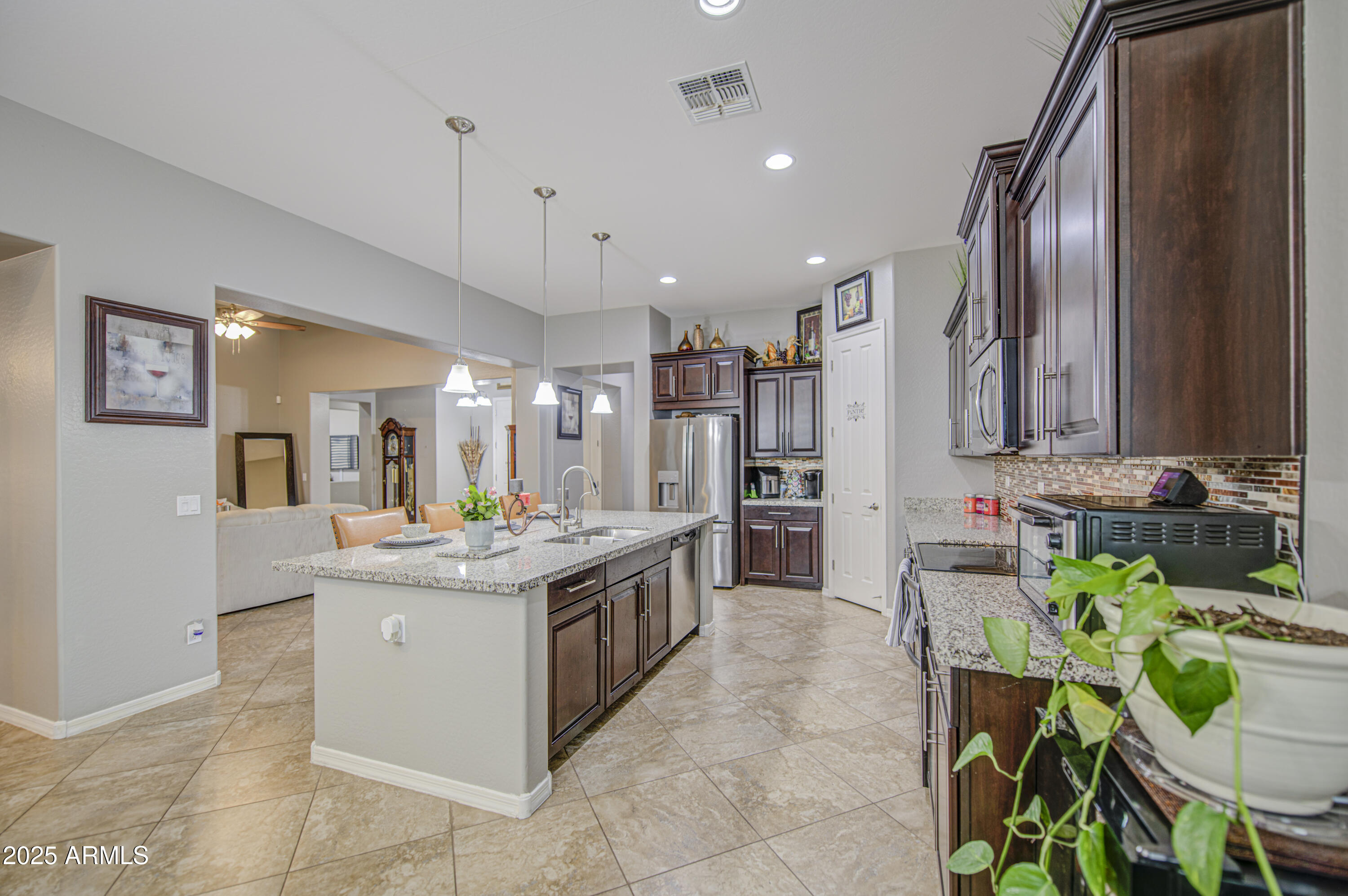 14304 West Coronado Road Goodyear, AZ 85395 - Photo 29 of 66 a kitchen with stainless steel appliances kitchen island granite countertop a stove and a sink