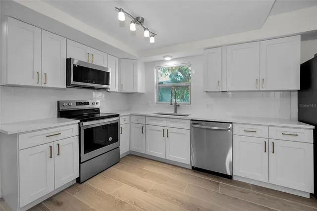 a kitchen with stainless steel appliances a refrigerator sink and microwave