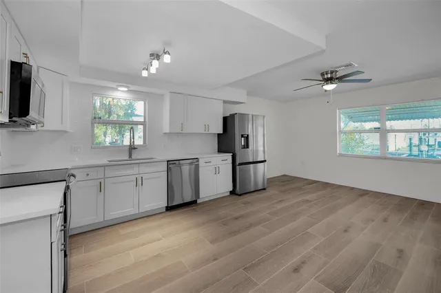 an empty room with wooden floor chandelier and windows