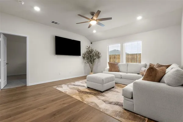 a living room with couches a flat screen tv and a large window
