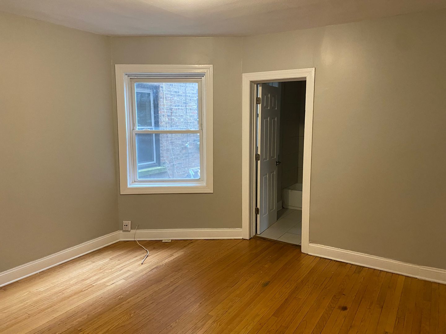 7822 South Kingston Avenue, Unit 1 Chicago, IL 60649 - Photo 3 of 15 an empty room with wooden floor and windows