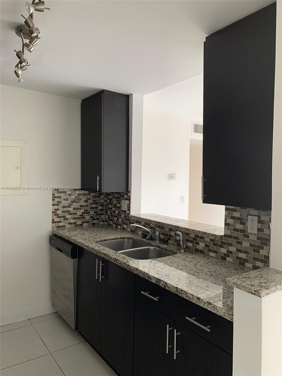 2150 Southwest 16th Avenue, Unit 409 Miami, FL 33145 - Photo 4 of 6 a bathroom with a granite countertop sink and a mirror