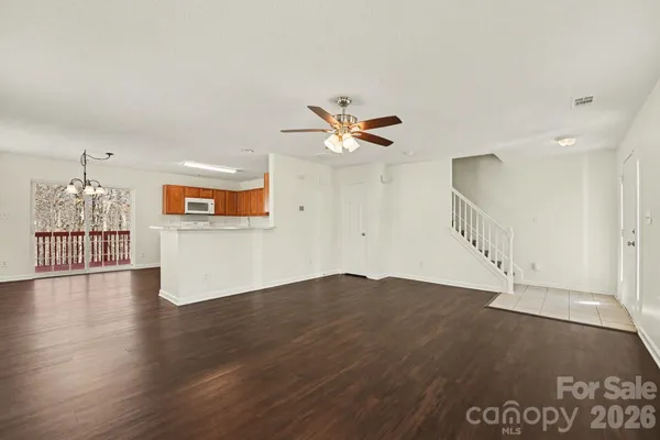 a view of an empty room with wooden floor and a ceiling fan