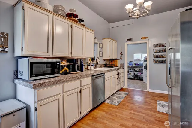 a kitchen with granite countertop a refrigerator a sink a stove and cabinets