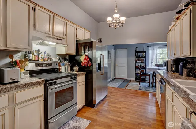 a kitchen with stainless steel appliances granite countertop a stove a sink dishwasher and a refrigerator with wooden cabinets