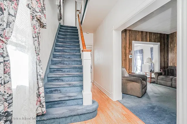 a view of a hallway to a livingroom with wooden floor and furniture
