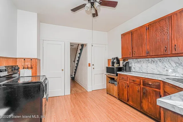 a kitchen with stainless steel appliances granite countertop a refrigerator a sink dishwasher a stove and white countertops with wooden floor