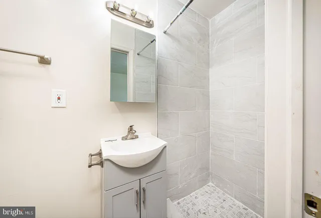 a bathroom with a sink shower and a mirror