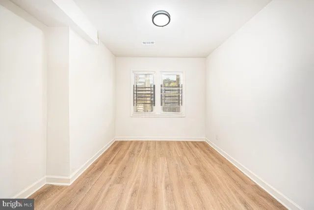 a view of empty room with wooden floor and fan