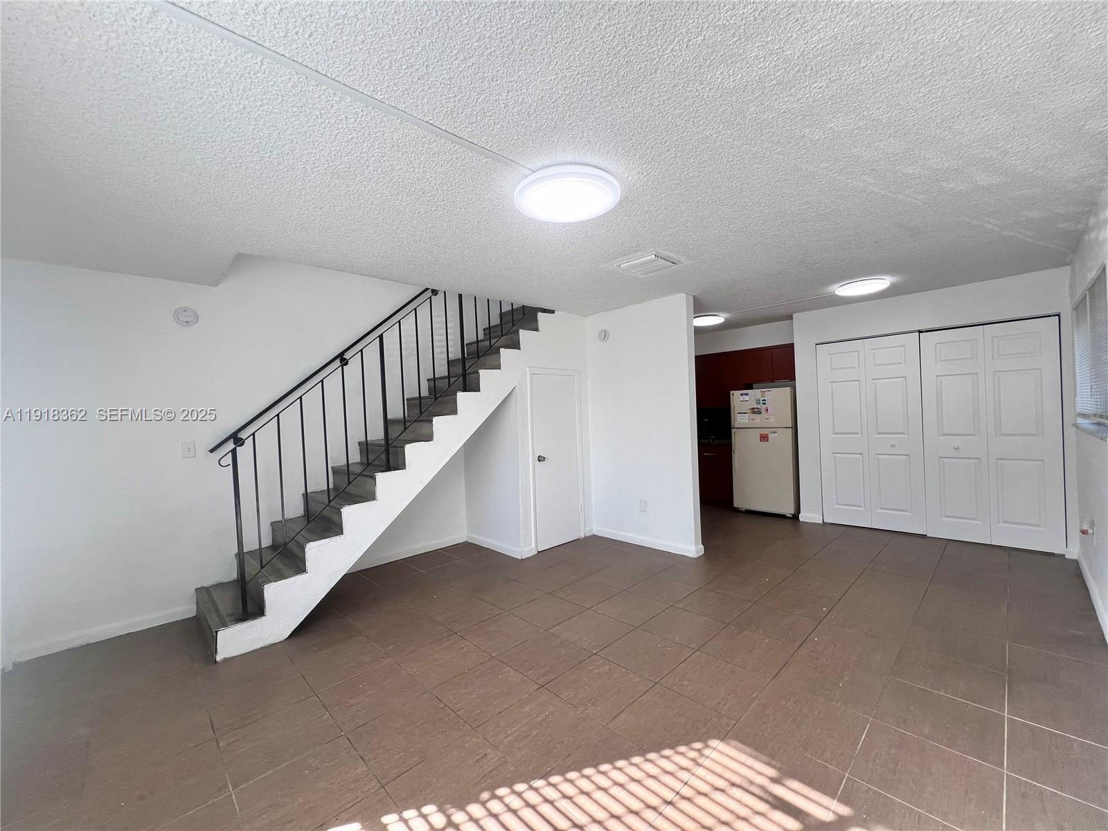 65 Northeast 59th Street, Unit 3 Miami, FL 33137 - Photo 3 of 10 a view of an empty room with stairs and a ceiling fan