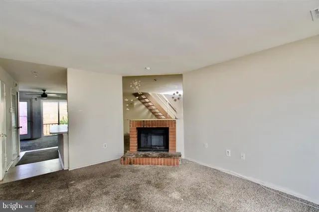 an empty room with wooden floor fireplace and windows