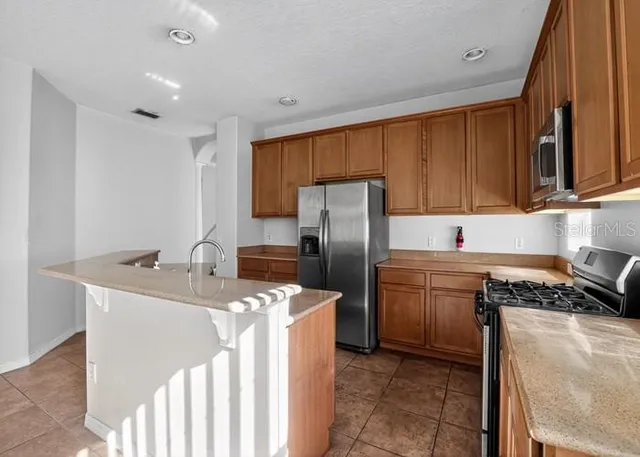 a kitchen with stainless steel appliances granite countertop a sink stove refrigerator and cabinets