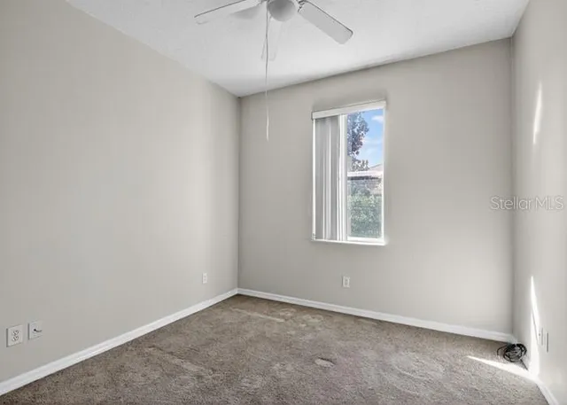 an empty room with a window and a ceiling fan