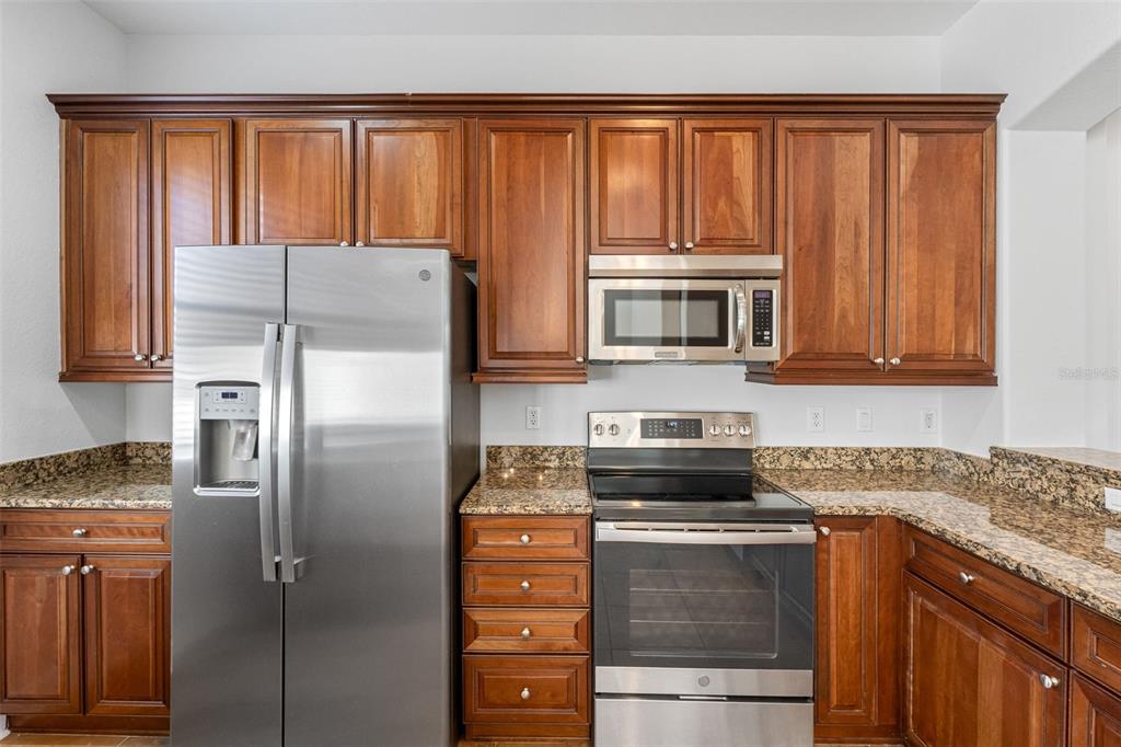 5902 Printery Street, Unit 105 Tampa, FL 33616 - Photo 16 of 54 a kitchen with granite countertop a refrigerator and a stove top oven