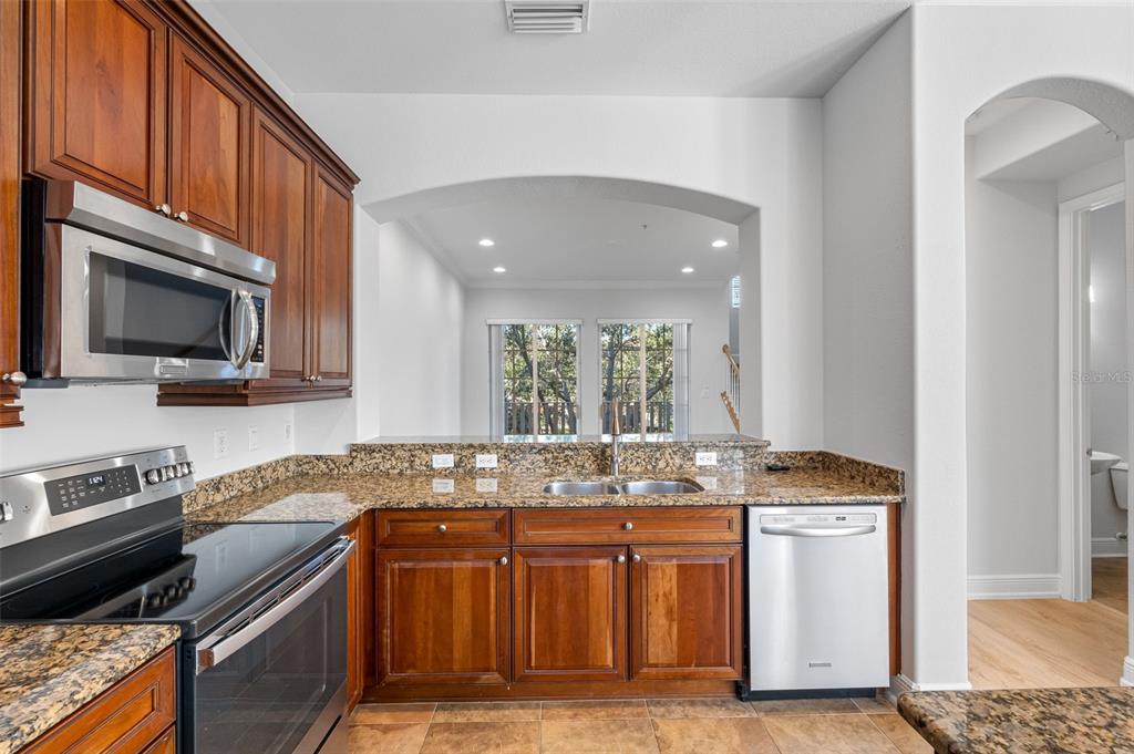 5902 Printery Street, Unit 105 Tampa, FL 33616 - Photo 17 of 54 a kitchen with granite countertop a stove top oven microwave and cabinets