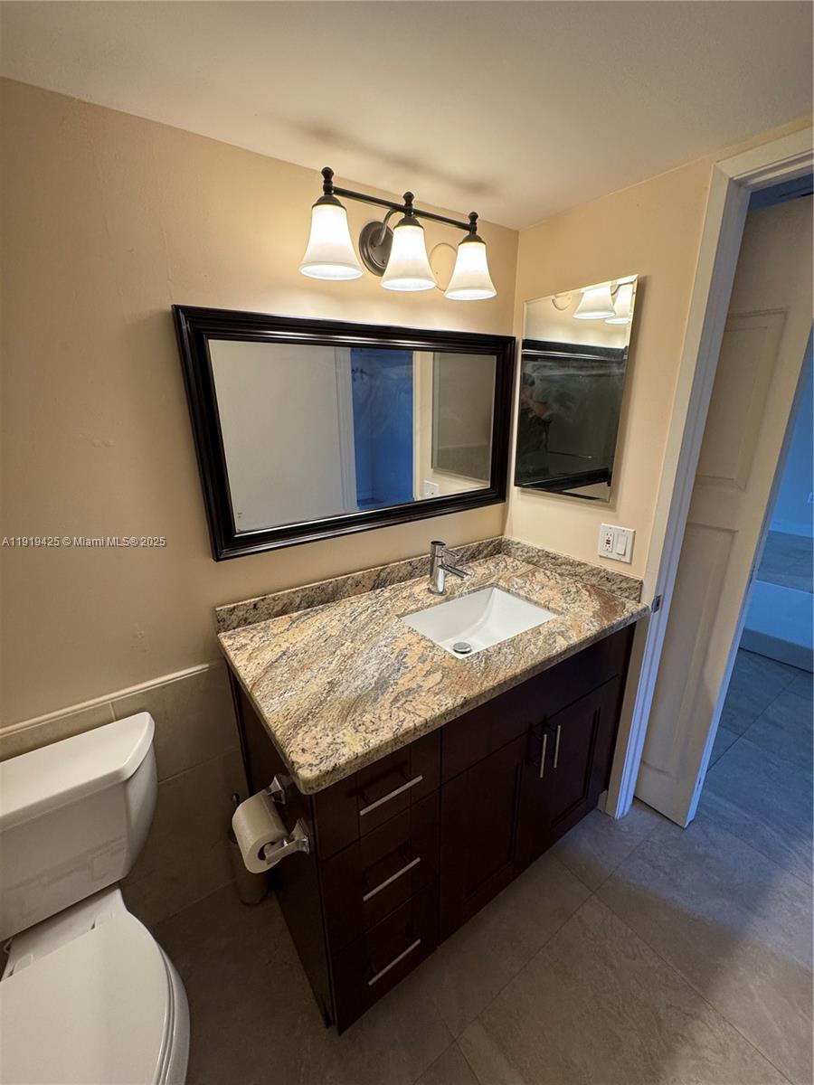 1001 Southwest 141st Avenue, Unit 107K Pembroke Pines, FL 33027 - Photo 13 of 28 a bathroom with a granite countertop toilet sink and mirror