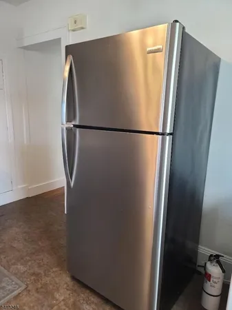 a view of a refrigerator in kitchen and an empty room