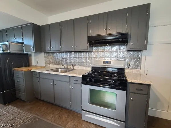 a kitchen with granite countertop wood cabinets and a stove top oven