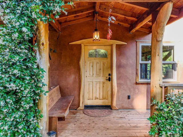 a view of a backyard with table and chairs potted plants and large trees