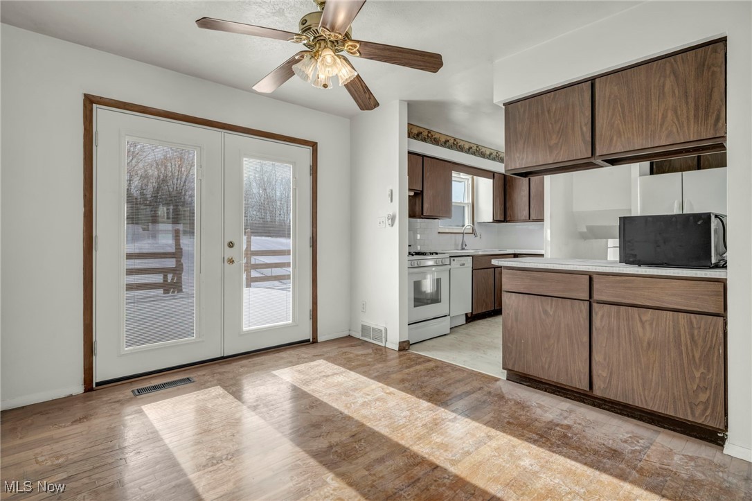 2514 Primewood Road Akron, OH 44305 - Photo 11 of 49 Kitchen featuring french doors, light countertops, white appliances, a ceiling fan, and backsplash
