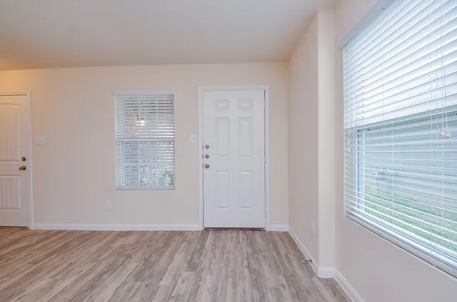 an empty room with wooden floor and windows