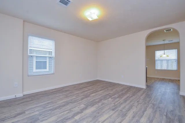an empty room with wooden floor and windows